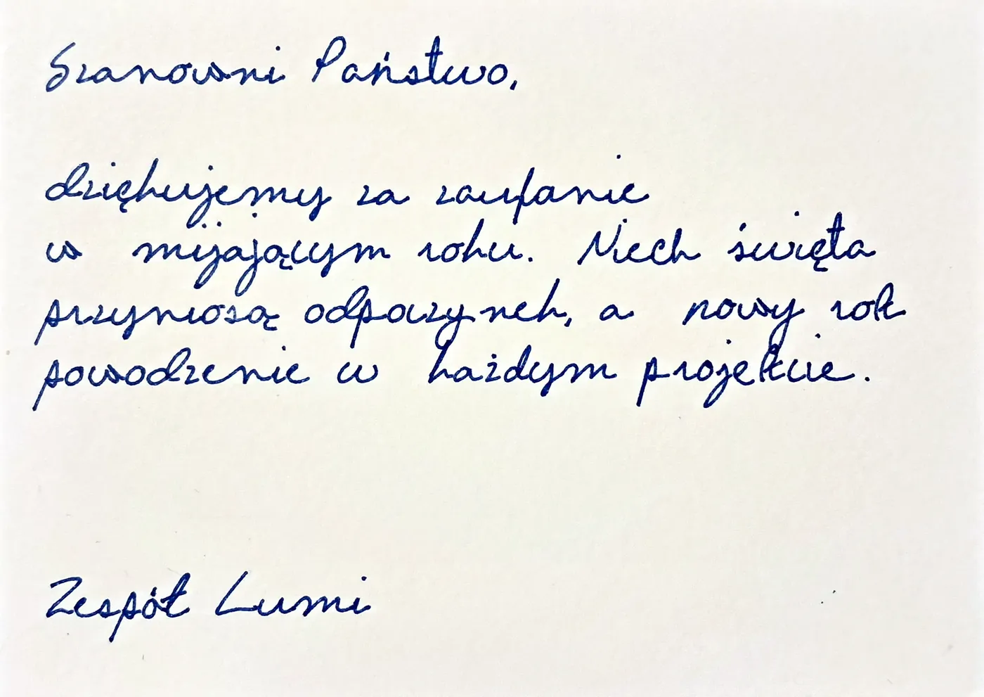 Ręcznie pisana kartka świąteczna dla klientów: „Szanowni Państwo, dziękujemy za zaufanie w mijającym roku. Niech święta przyniosą odpoczynek, a nowy rok powodzenie w każdym projekcie.” podpisana „Zespół Lumi”