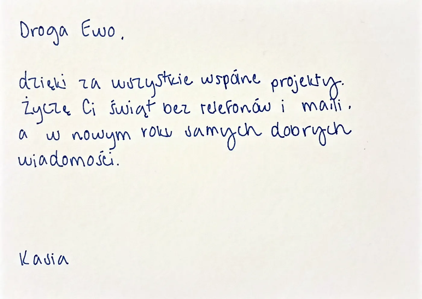 Ręcznie pisana kartka świąteczna dla partnerki biznesowej: „Droga Ewo, dzięki za wszystkie wspólne projekty. Życzę Ci świąt bez telefonów i maili, a w nowym roku samych dobrych wiadomości.” podpisana „Kasia”